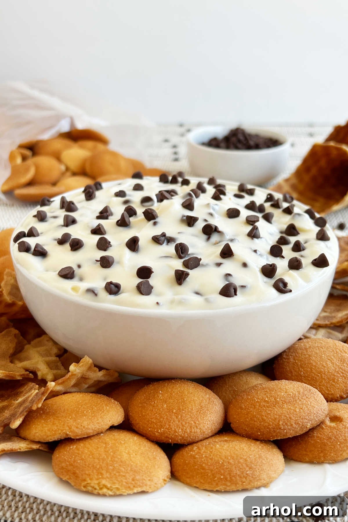 bowl of cannoli dip on table with vanilla wafers and waffle cone pieces