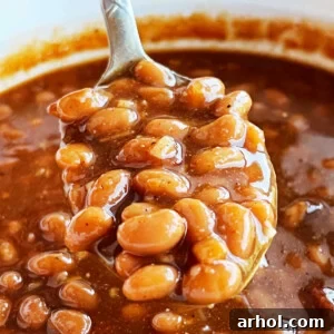 Easy baked beans with brown sugar on a serving spoon, showcasing the rich, savory sauce.