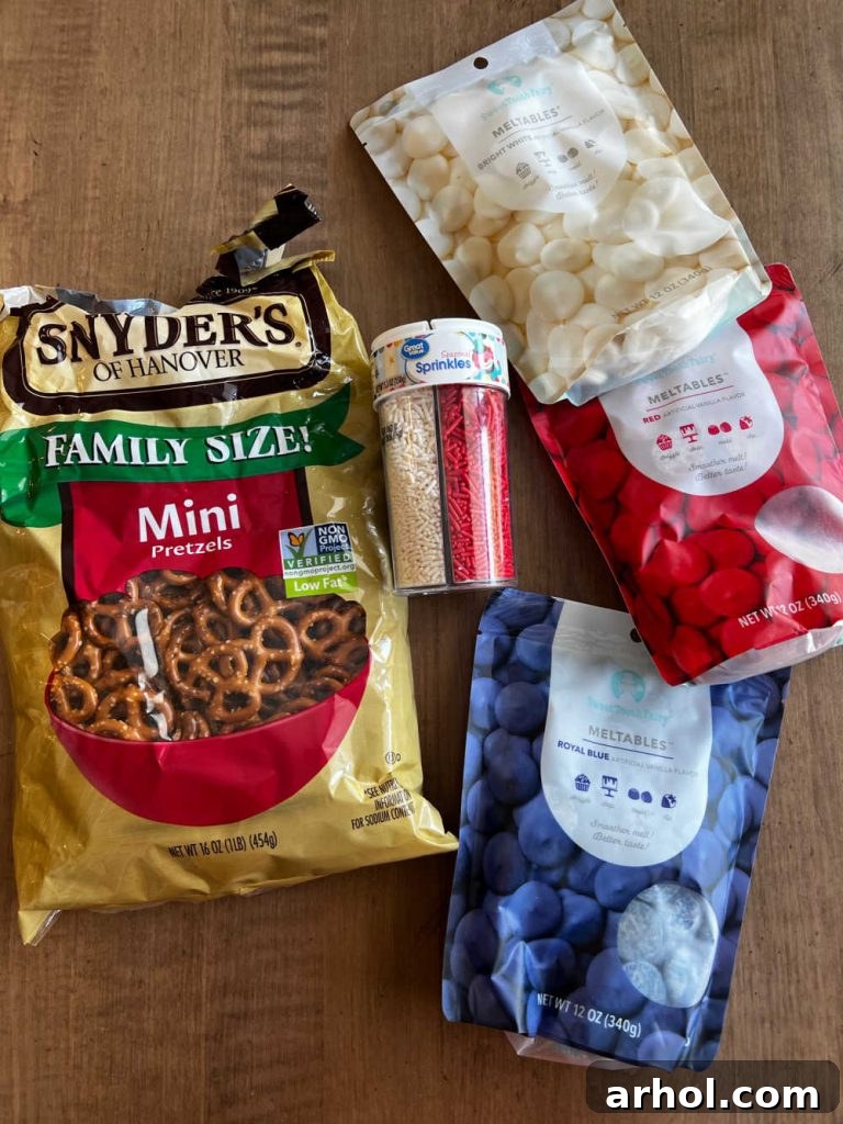 Mini pretzels, red, white, and blue candy melts, and patriotic sprinkles arranged on a table, ready for dipping.