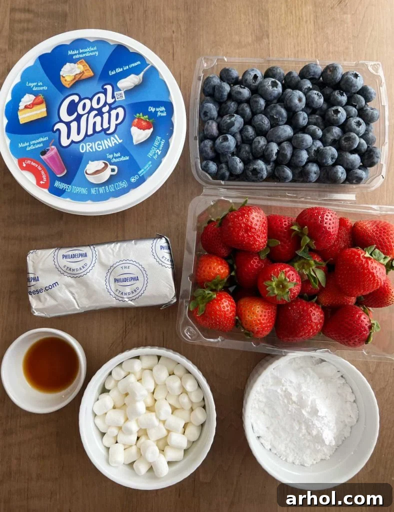 All the fresh ingredients laid out for Red White and Blue Cheesecake Salad: fresh strawberries, blueberries, Cool Whip, cream cheese, vanilla extract, mini marshmallows, and powdered sugar.