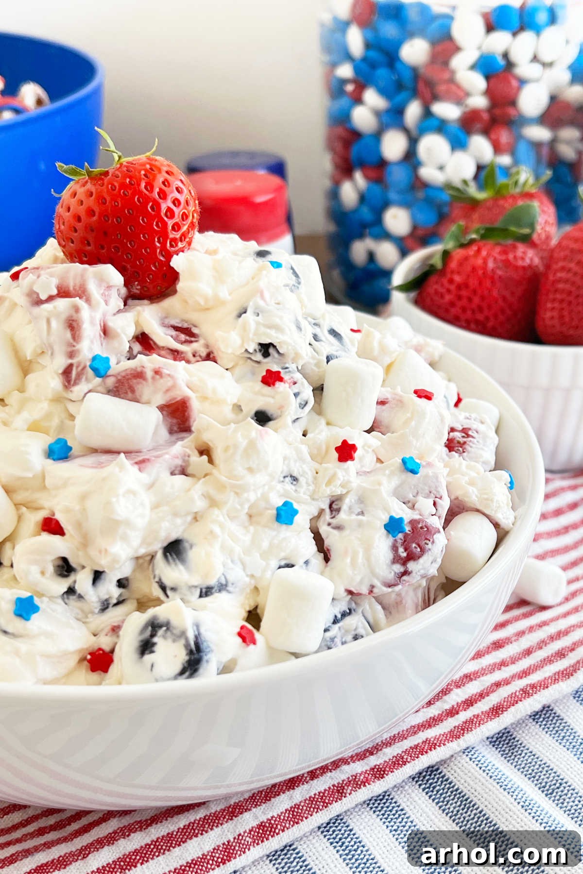A festive bowl of Red White and Blue Cheesecake Salad with patriotic sprinkles and mini marshmallows, ready to be served on a 4th of July table.