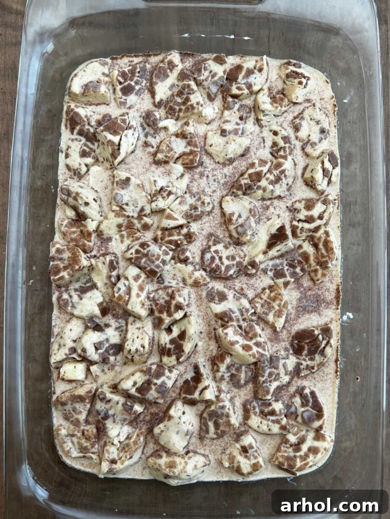 sliced cinnamon roll pieces with egg custard in baking dish
