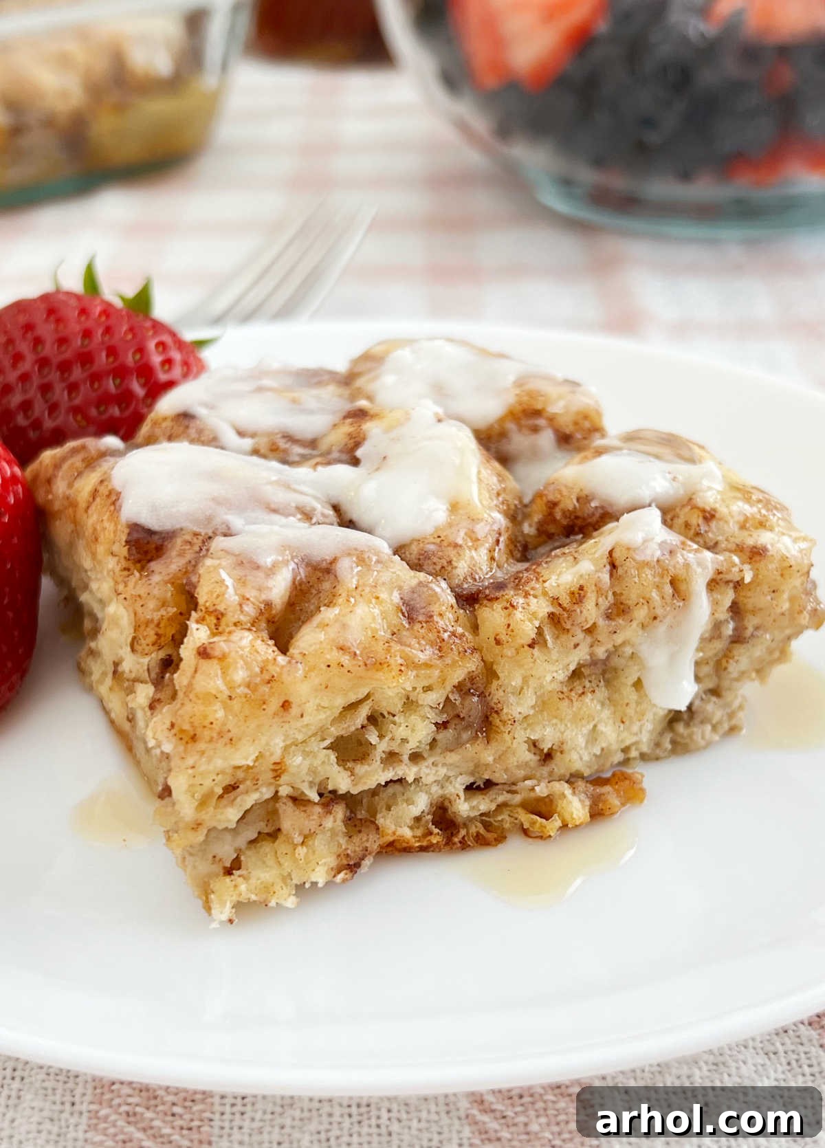 piece of cinnamon roll casserole on plate with strawberries