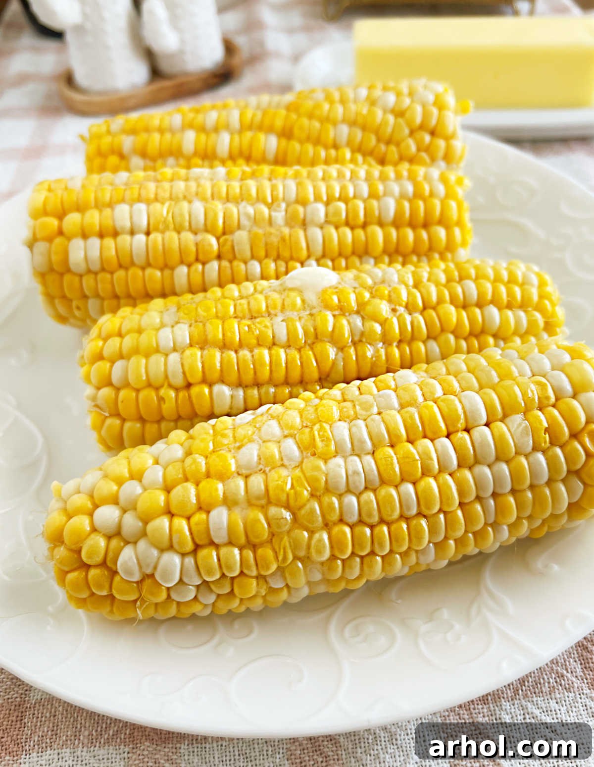 Perfectly cooked microwave corn on the cob with melted butter on a white plate, ready to be enjoyed.