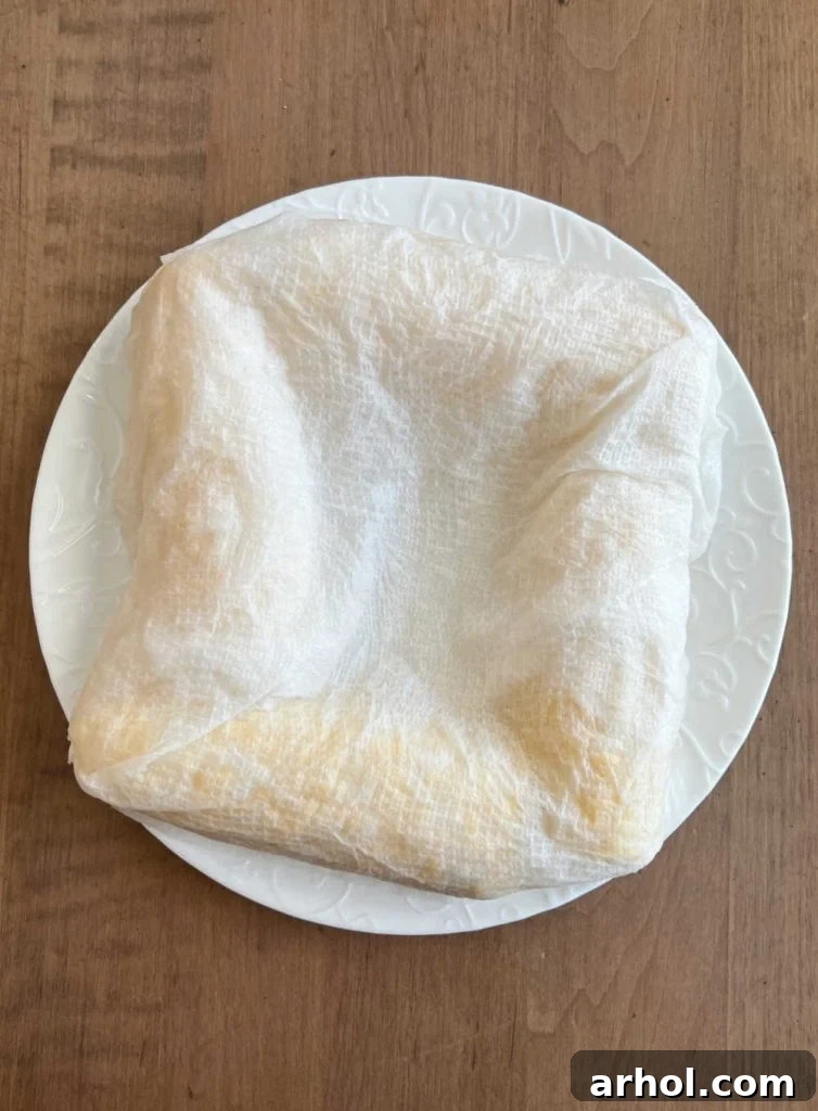 Ears of corn on the cob completely wrapped in damp paper towels, ready for microwaving.