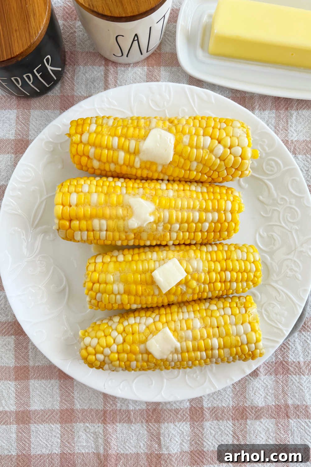 A beautifully set plate of microwave corn on the cob, generously buttered and ready for serving on a rustic table.