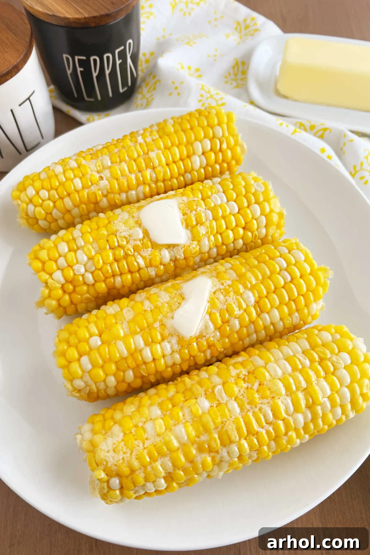 A beautifully presented plate of corn on the cob, glistening with melted butter, placed on a rustic table, inviting enjoyment.