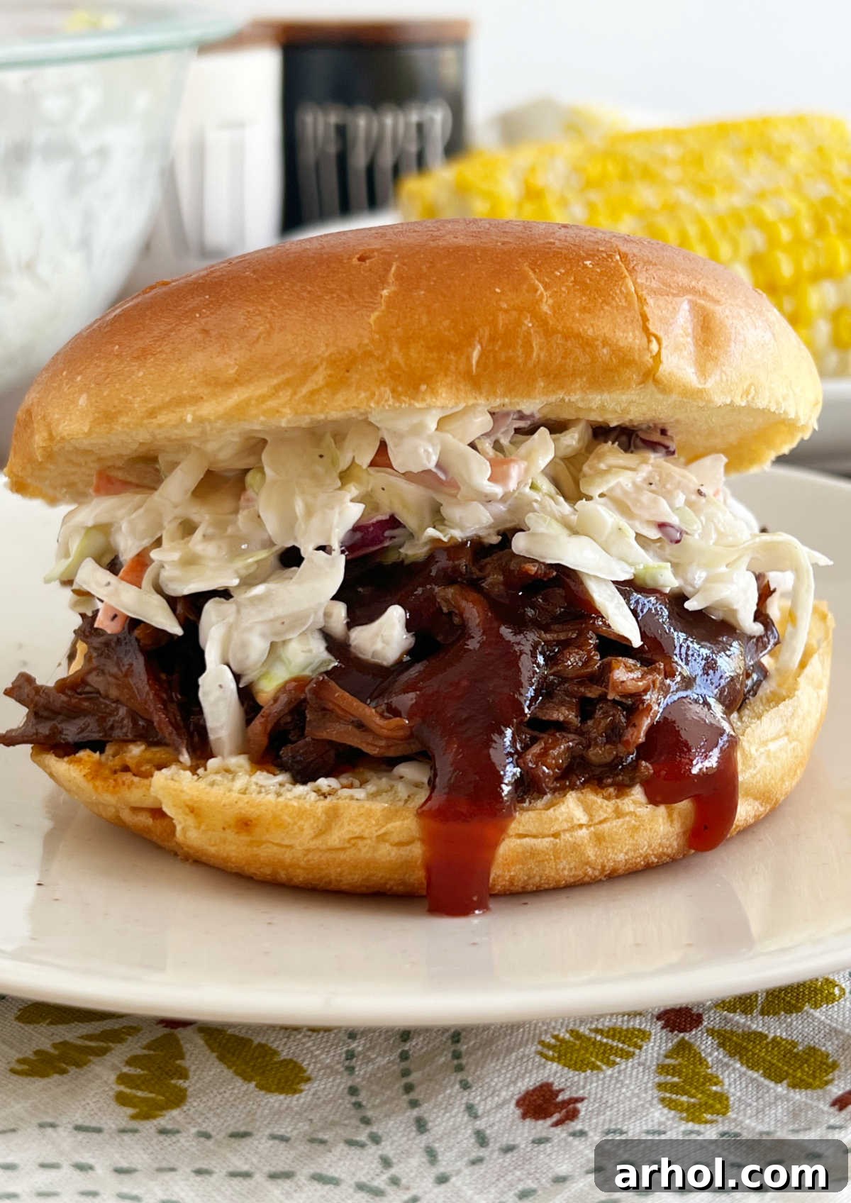 slow cooker bbq beef sandwich with coleslaw and bbq sauce on plate.
