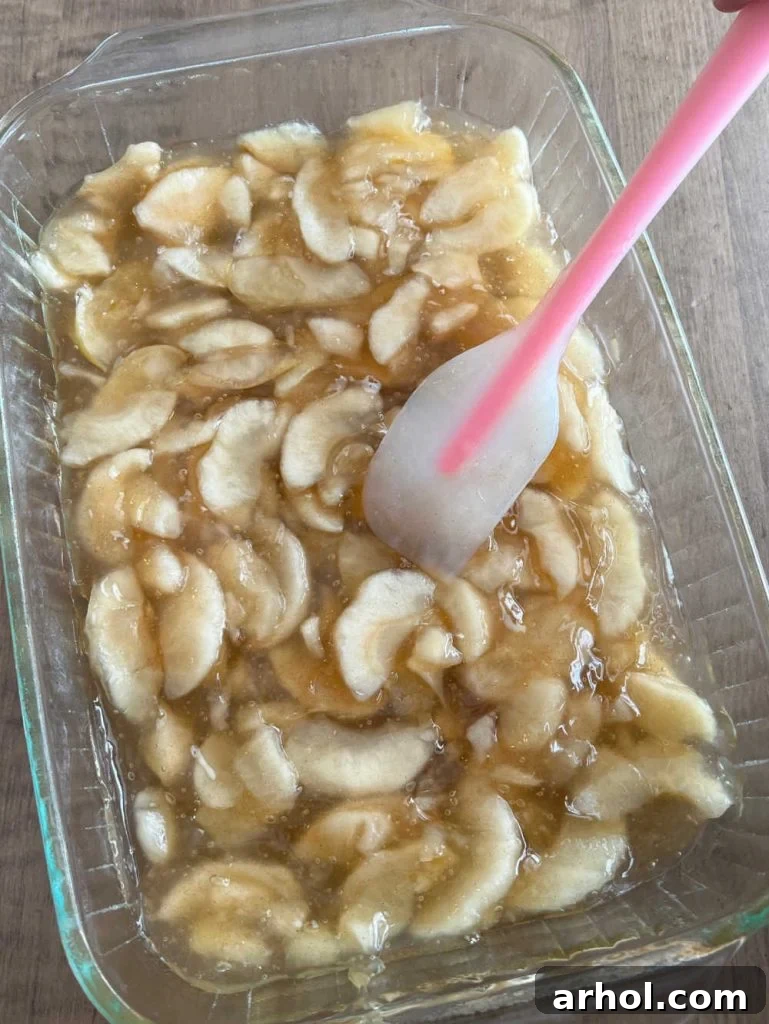 Effortless Caramel Apple Dump Cake 5 Spreading canned apple pie filling evenly into a 9x13 inch baking dish.