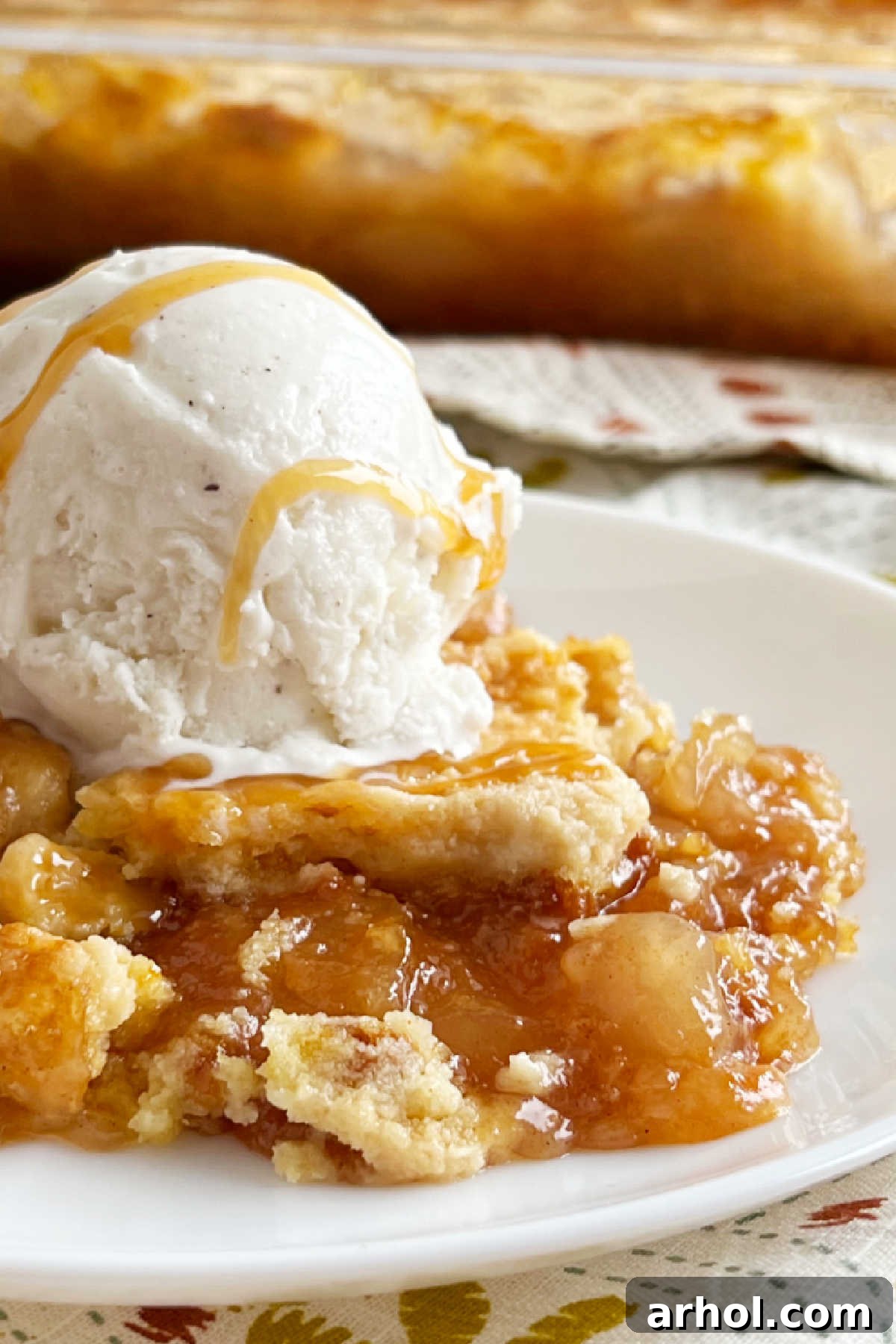 Effortless Caramel Apple Dump Cake 8 Warm caramel apple dump cake served on a plate with a generous scoop of vanilla ice cream and a drizzle of caramel sauce.