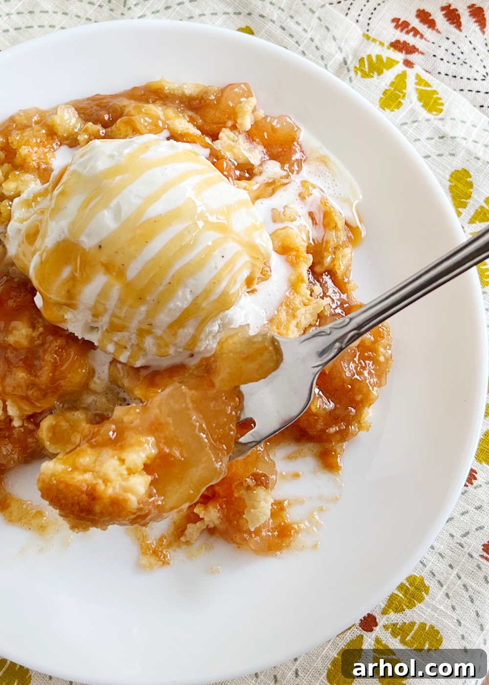 Effortless Caramel Apple Dump Cake 9 Close-up of a fork lifting a gooey piece of caramel apple dump cake, showing the melted caramel and soft apples.