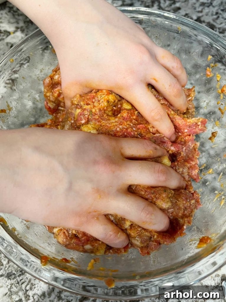 hands mixing meatloaf mixture in bowl.