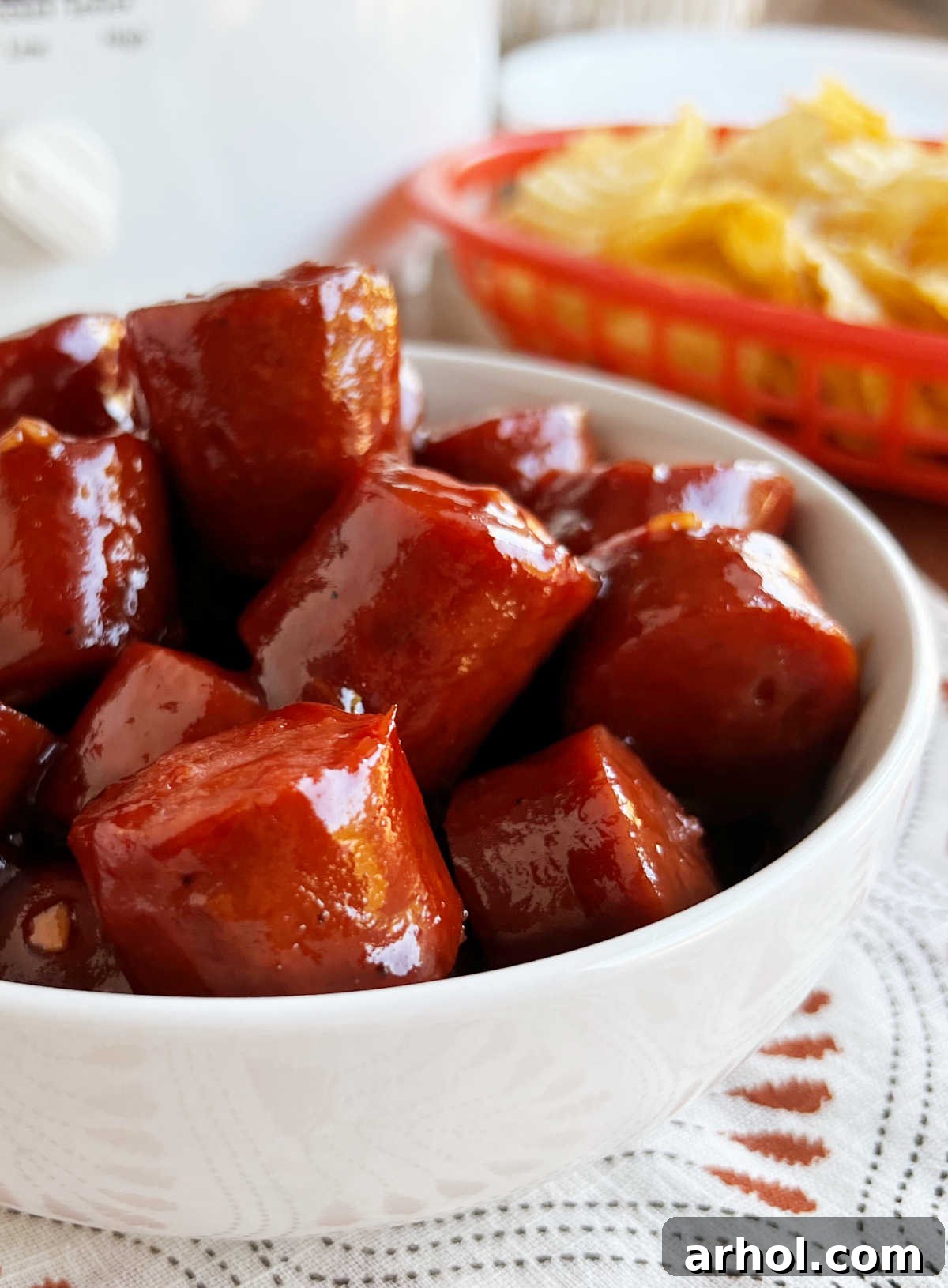A beautifully presented bowl of slow cooker kielbasa bites with BBQ sauce, garnished and ready to be served on a rustic wooden table, highlighting their appeal.