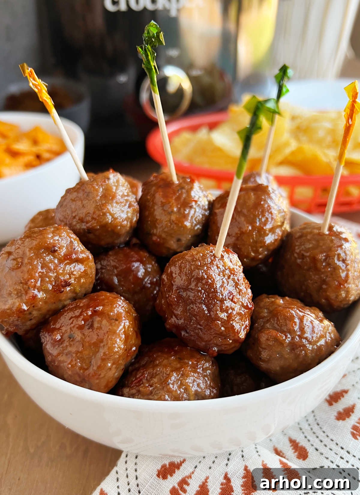 crockpot grape jelly meatballs with party toothpicks in serving bowl on table.
