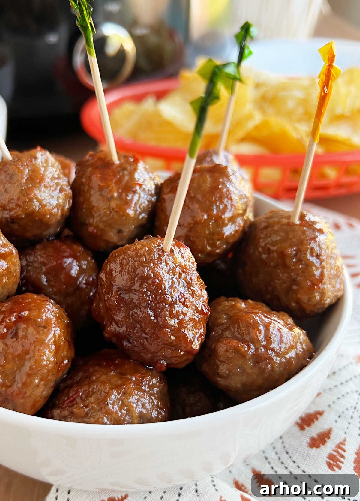 crock pot grape jelly meatballs in bowl with party toothpicks.