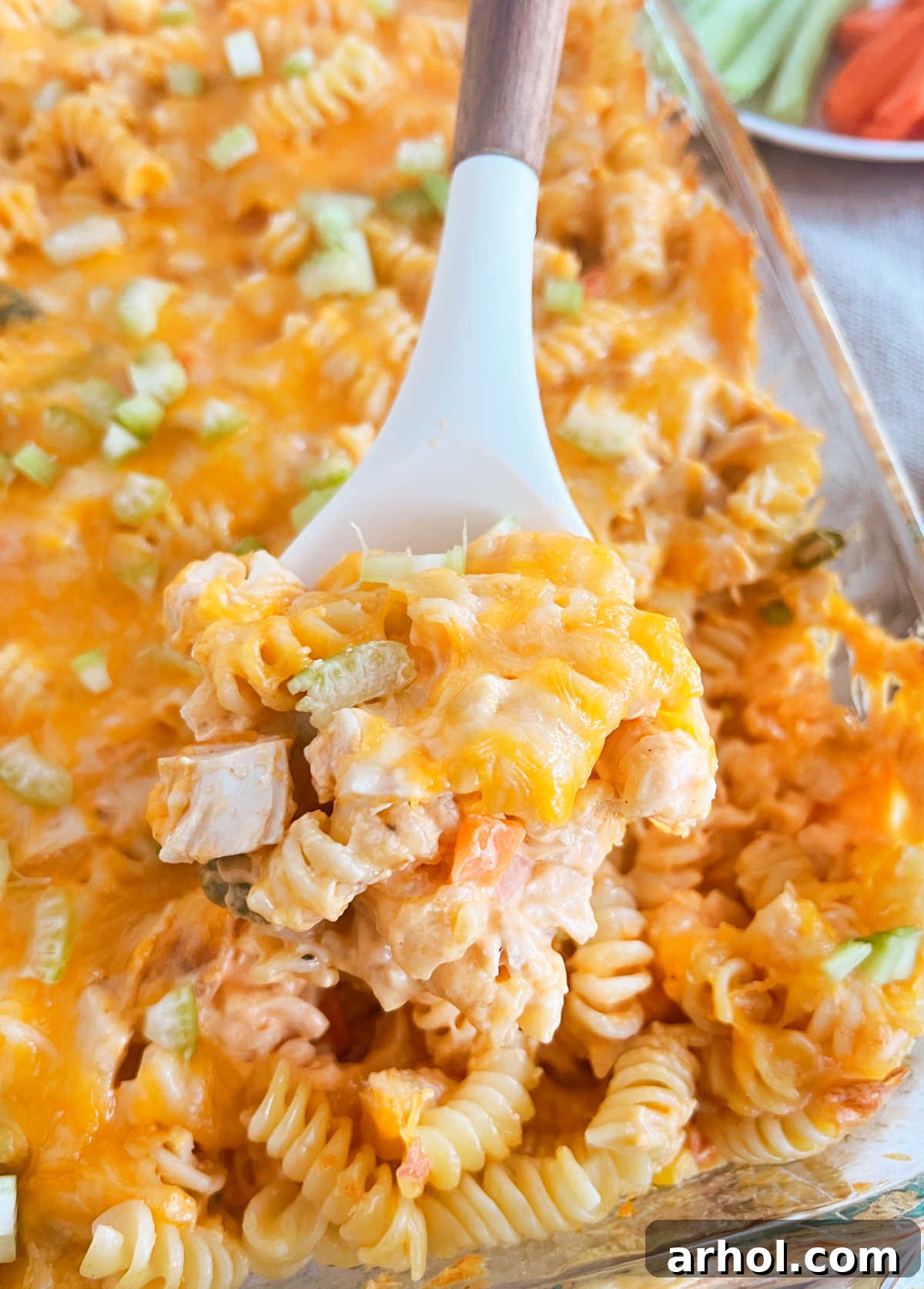 Creamy Buffalo Chicken Casserole with pasta and veggies on a spoon, ready to serve.
