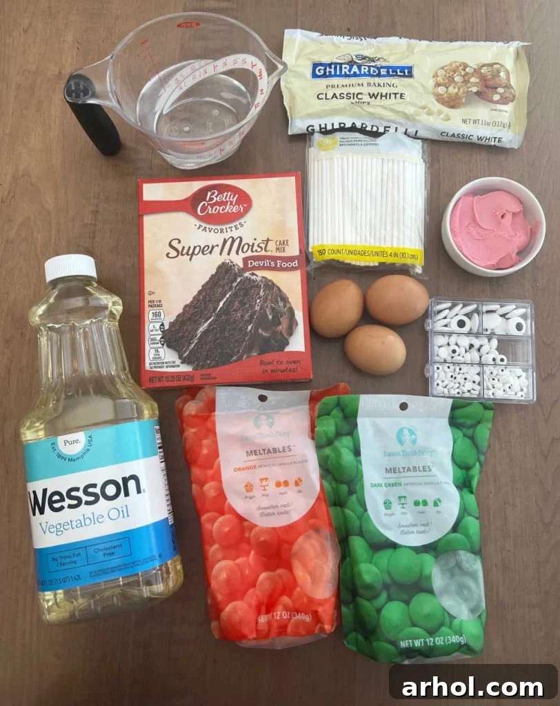Essential ingredients laid out for Halloween cake pops: cake mix, frosting, various colored candy melts, white chocolate chips, and candy eyes.