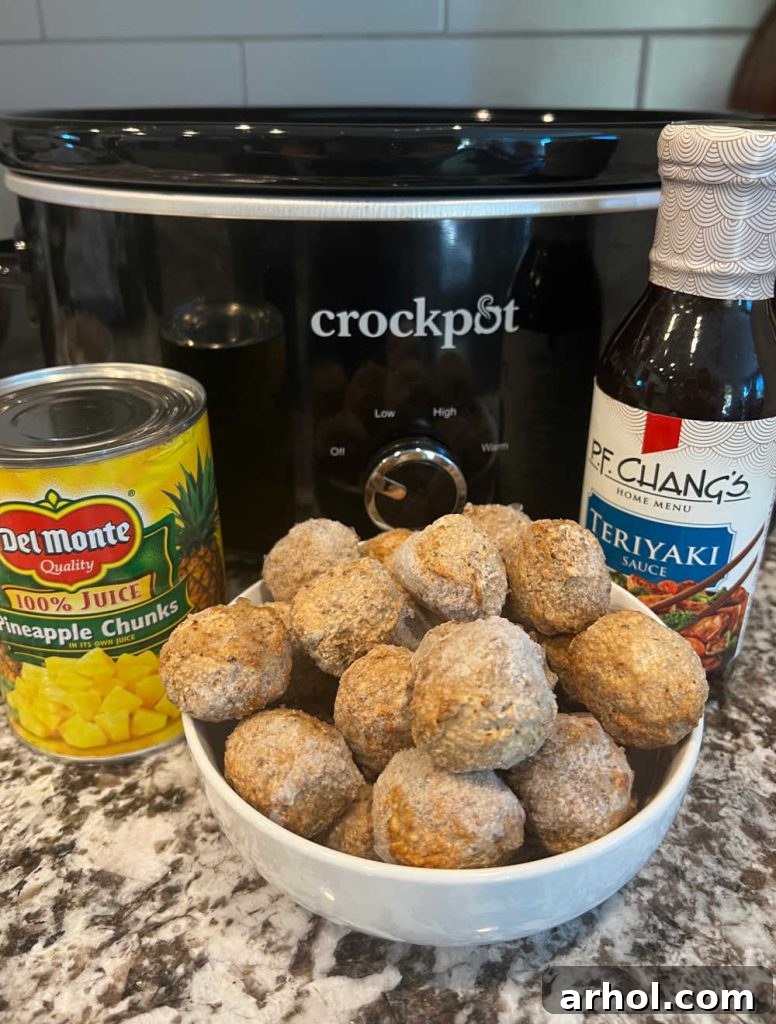 Three simple ingredients: a bag of frozen meatballs, a can of pineapple chunks, and a bottle of teriyaki sauce, ready for the crockpot.