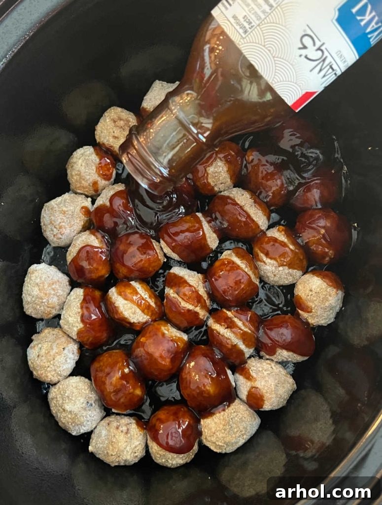 Pouring teriyaki sauce directly over frozen meatballs in a crockpot, ensuring even coating.