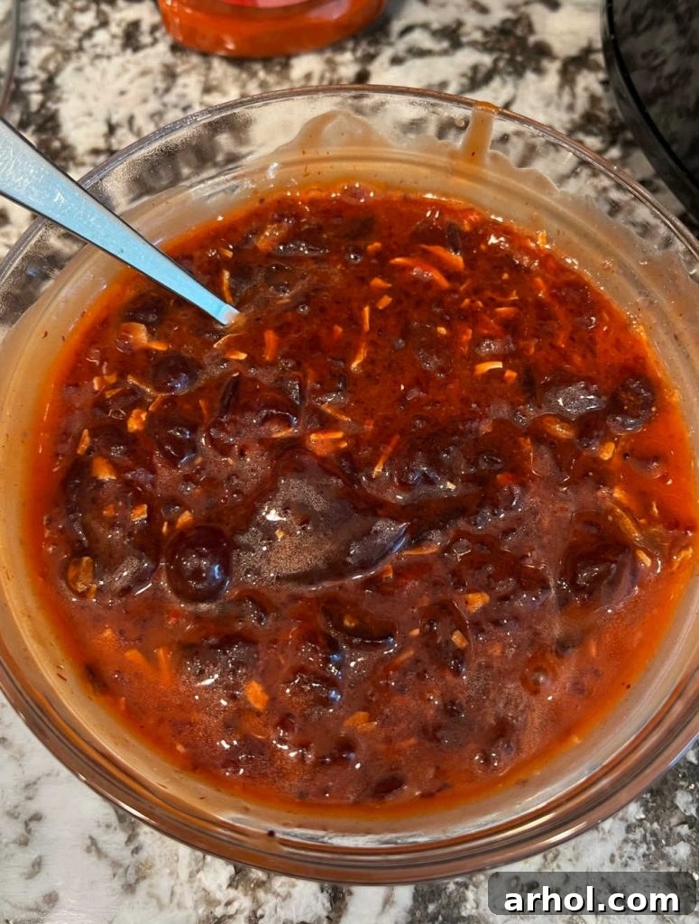 A small bowl showing cranberry sauce, dry onion soup mix, and Catalina salad dressing being mixed together.