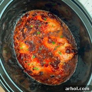 A square image of slow cooker cranberry chicken, appealing and ready to be served.