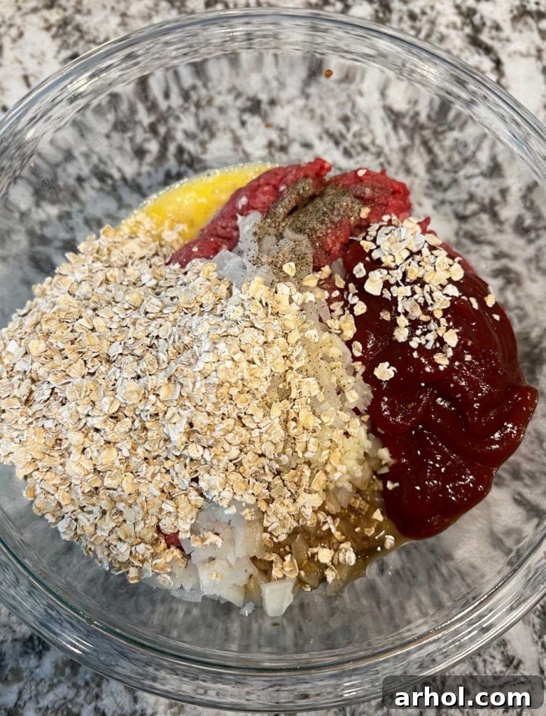 All the meatloaf ingredients, including ground beef, oats, and seasonings, combined in a large mixing bowl, ready for blending.