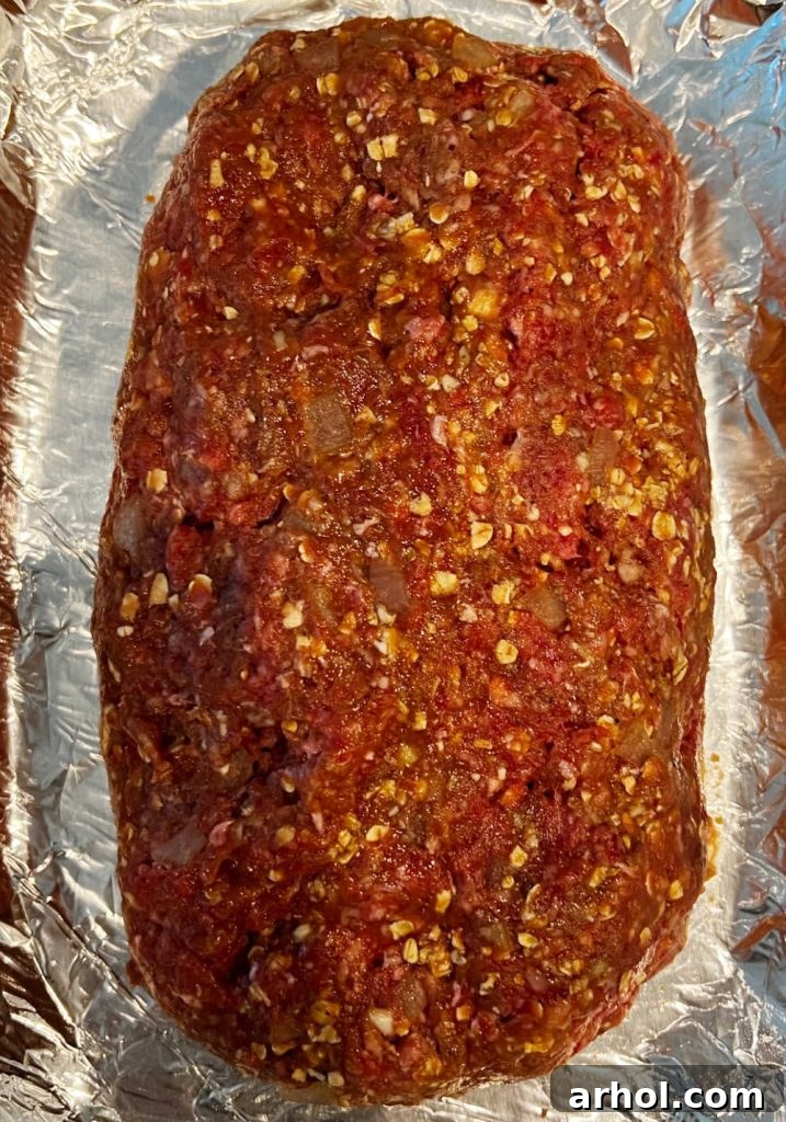 An unbaked meatloaf, shaped in a baking dish and topped with a ketchup glaze, ready for the oven.