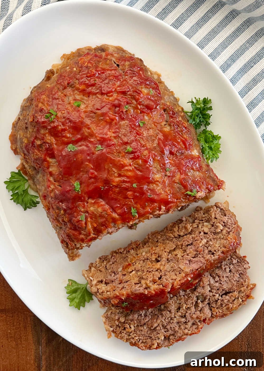 A beautifully presented meatloaf with ketchup glaze and fresh parsley, ready to be served.
