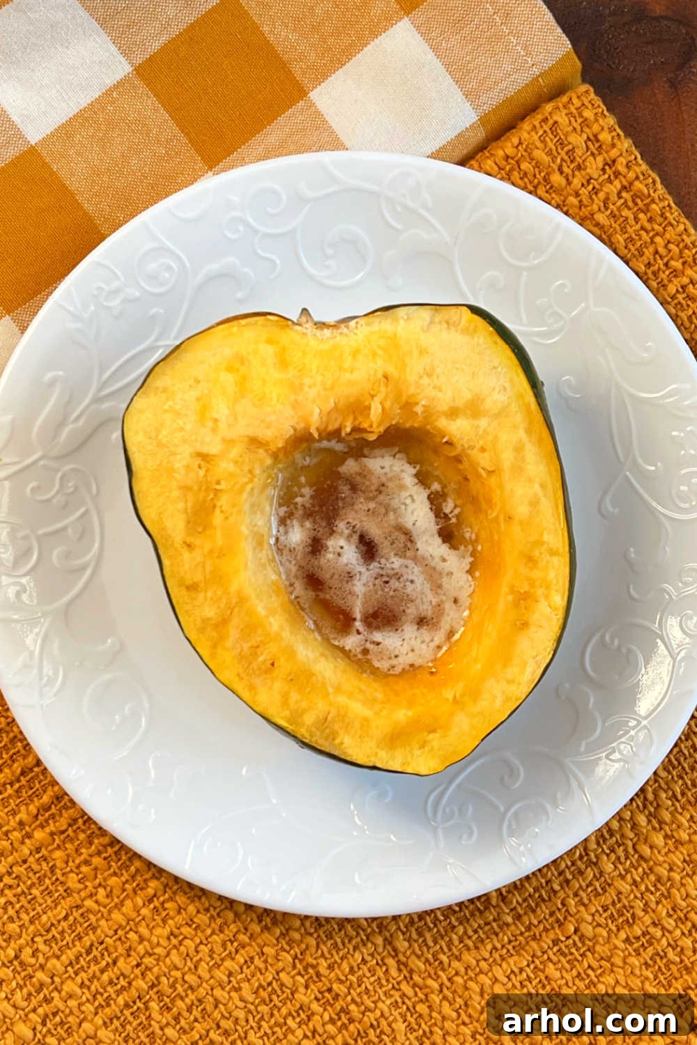 Microwave acorn squash half with melted butter and brown sugar on plate, ready to serve.