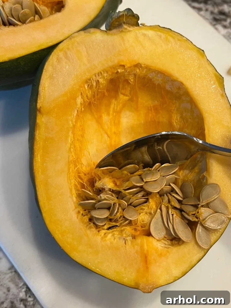 Scraping seeds out of acorn squash with a spoon.