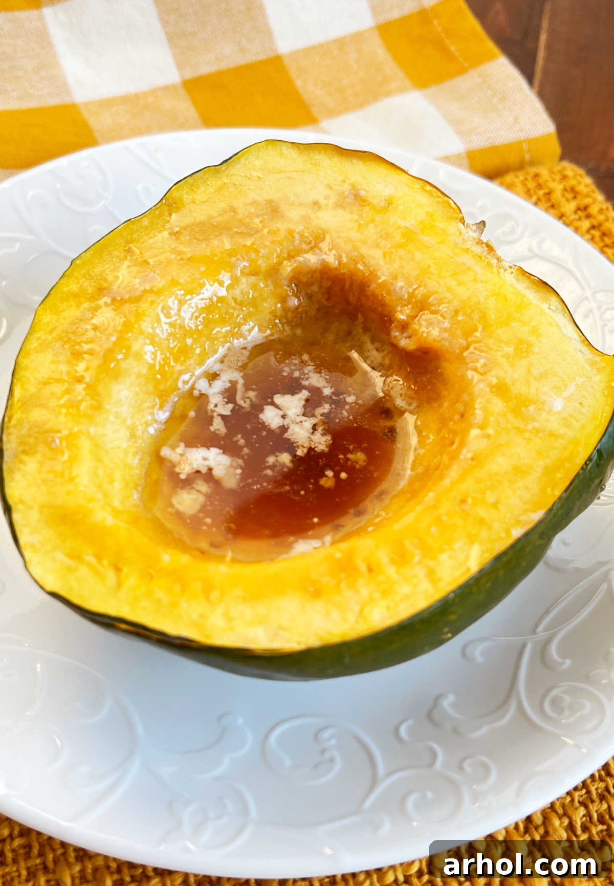 Microwaved acorn squash half with melted butter and brown sugar center, ready to be enjoyed.