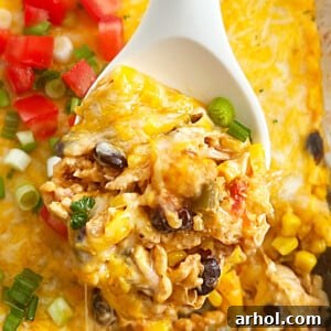 Fiesta chicken casserole with rice and cheese on a serving spoon.