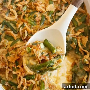 Campbell's green bean casserole with fried onions on a serving spoon, showcasing its rich texture.