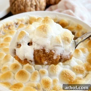 sweet potato casserole made with canned yams and marshmallows on serving spoon.