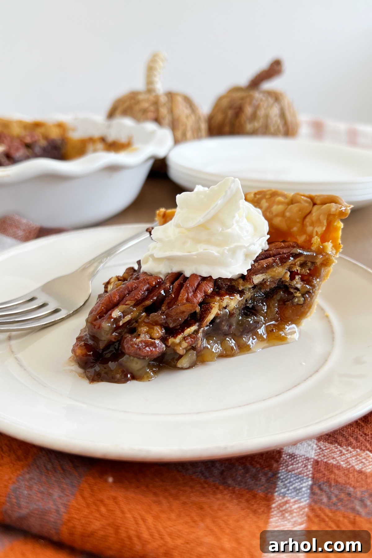 Grandma's bourbon chocolate pecan pie with a generous dollop of whipped cream on a festive plate, ready to be enjoyed during holiday celebrations.
