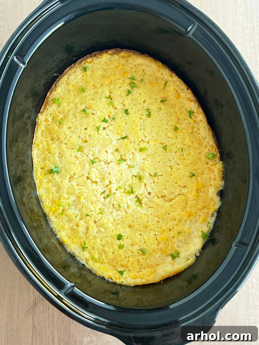 Golden-brown Jiffy Crock Pot Corn Casserole simmering in the slow cooker, ready to be served.