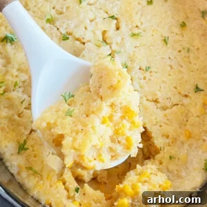 Crock Pot Corn Casserole with Jiffy Mix on a white serving spoon.