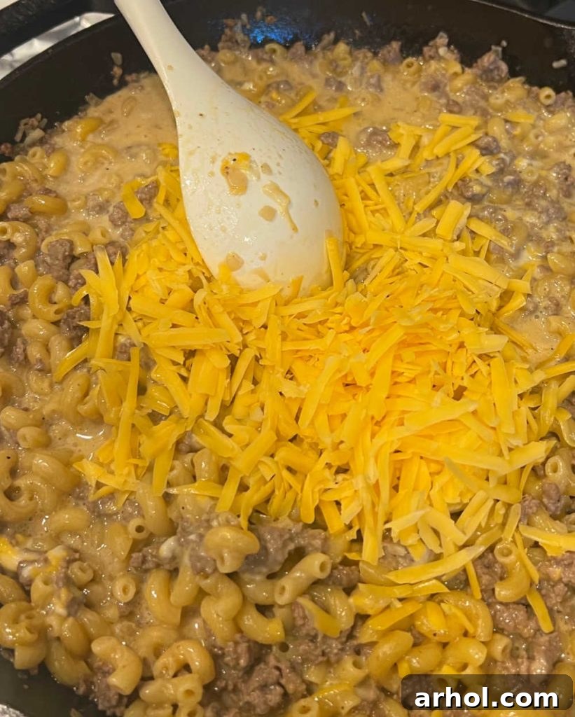 stir shredded cheddar cheese with hamburger mixture.