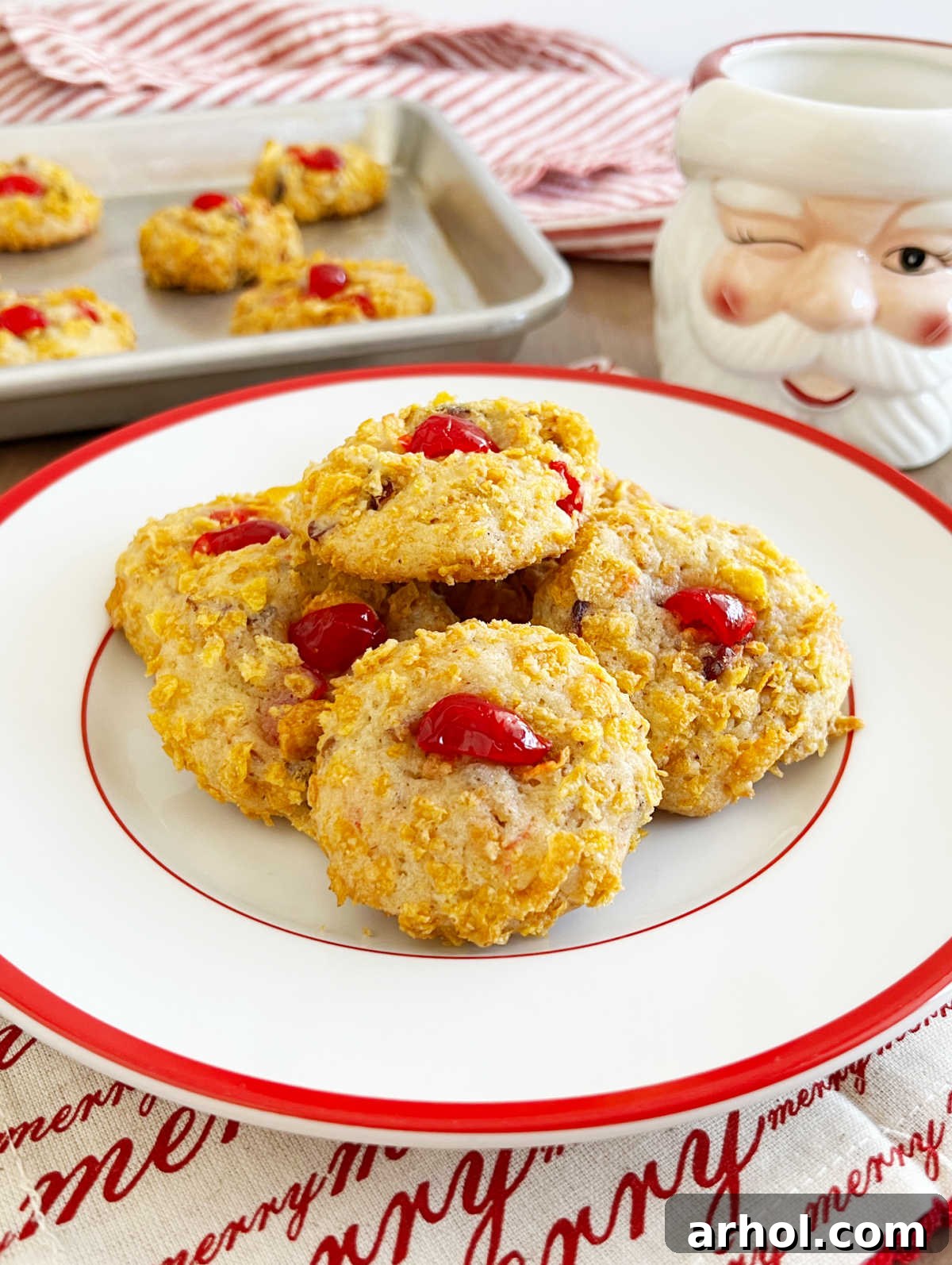 Cherry wink cookies on a festive Christmas plate with a Santa mug, evoking holiday cheer.