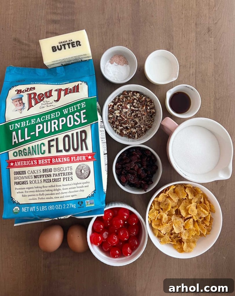 A flat lay of fresh ingredients including flour, butter, maraschino cherries, cornflakes, eggs, sugar, vanilla extract, milk, and chopped pecans, ready for baking cherry wink cookies.