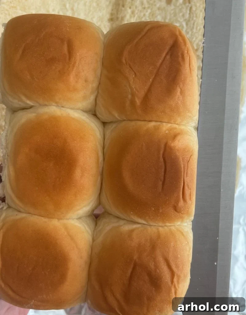 Aloha Turkey Sliders 4 A bread knife being used to slice a block of Hawaiian rolls in half horizontally.