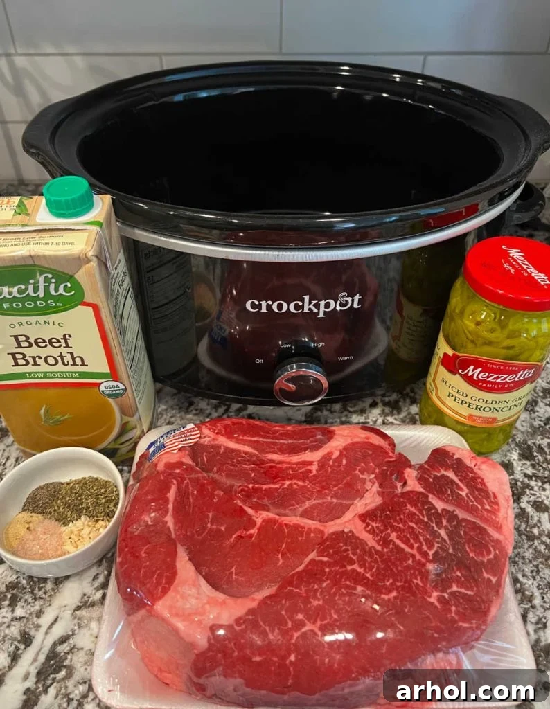 boneless beef chuck roast, beef broth, seasonings, pepperoncini peppers, and a slow cooker, all ready for preparing Italian beef.