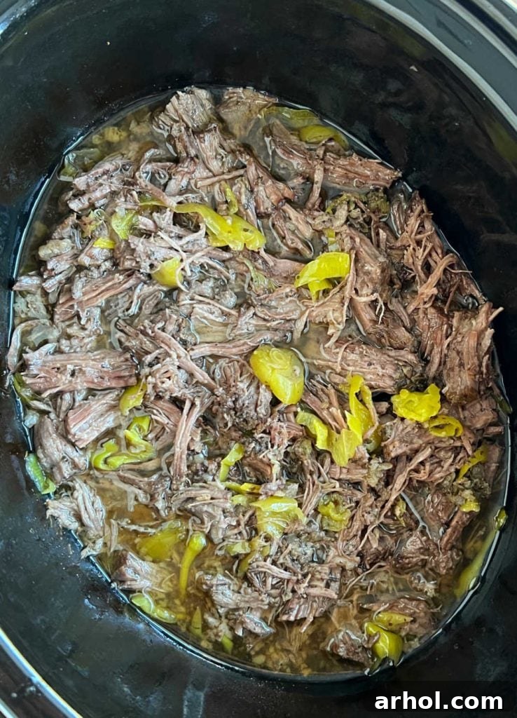 shredded italian beef with peppers in crockpot, ready to be served.