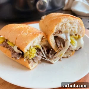 crock pot Italian beef sandwiches with gooey melted provolone cheese on a plate.