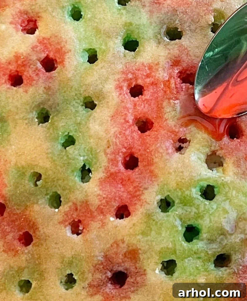 Pouring the red and green Jell-O mixture into the holes of the cake using a spoon.