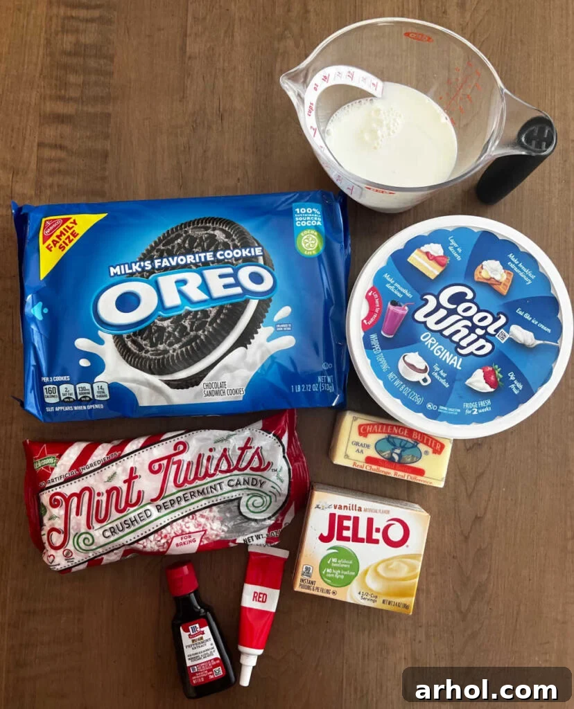 Ingredients laid out on a table: Oreo cookies, milk, Cool Whip, butter, instant vanilla pudding mix, peppermint extract, red gel food coloring, and peppermint candy canes.