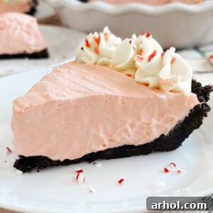 Peppermint pie with Oreo cookie crust on a plate, adorned with whipped cream and crushed candy canes.