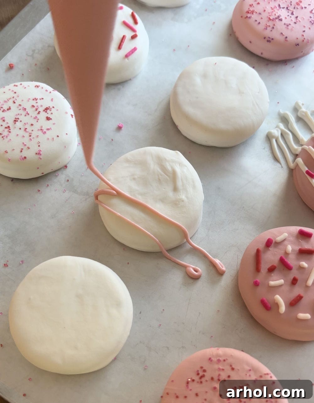Irresistible White Chocolate Covered Oreos 5 Drizzling pink candy coating creatively over freshly dipped white chocolate Oreo cookies for added decoration.