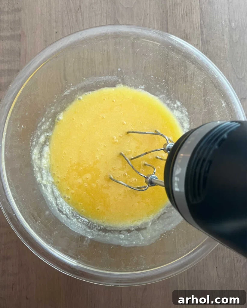 Large eggs being lightly beaten in a mixing bowl with an electric mixer.