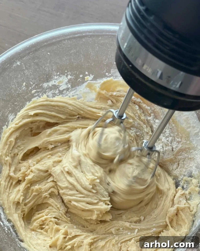 All-purpose flour and baking powder being mixed into the wet ingredients to form the pizzelle batter.